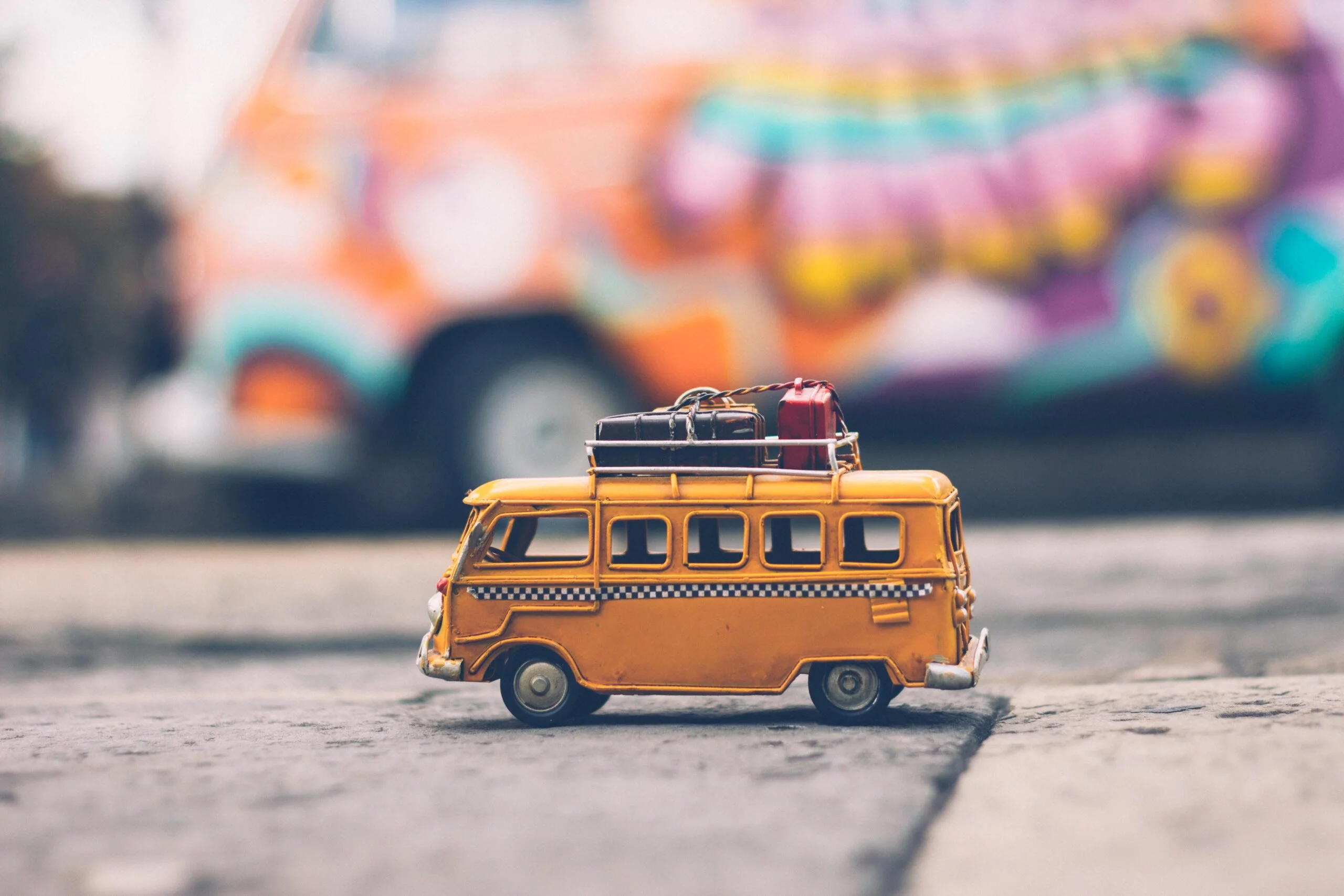 miniature yellow bus with luggage on top.