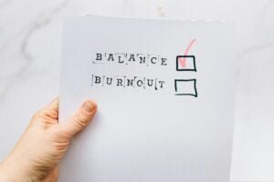 hand holding a carboard with two checkboxes: Balance and Burnout.