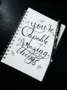 Pen on top of a Notebook with a note: "You're capable of amazing things"