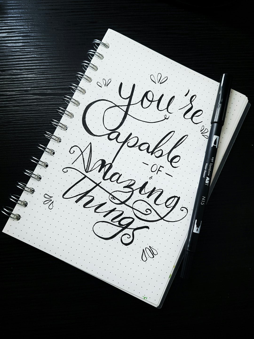 Pen on top of a Notebook with a note: "You're capable of amazing things"