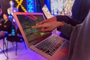 A vibrant scene with hands pointing at a computer with code on display, suggesting tech focus.