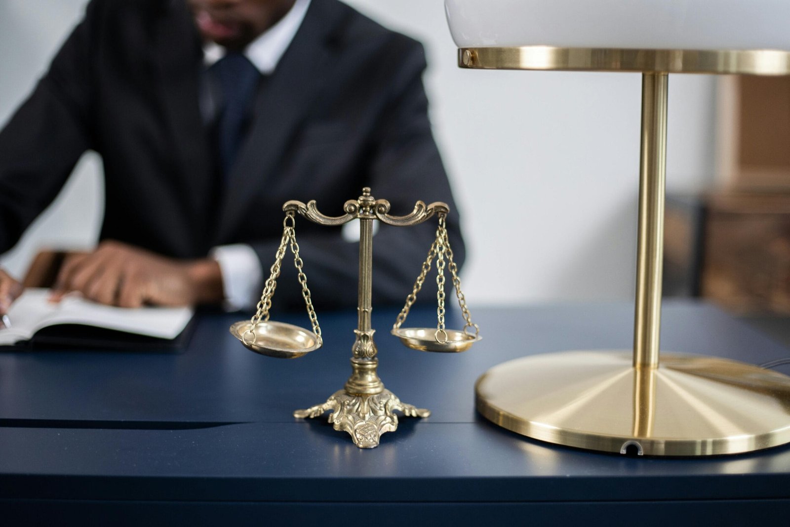 The Effort Paradox: Does It Take Equal Energy to Hurt or Help? 1 Elegant legal office with a close-up of golden scales of justice on a sleek dark desk.