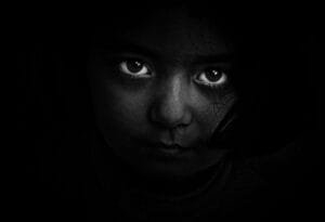 Intense black and white portrait of a child with captivating eyes, evoking mystery and emotion.