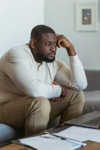 A thoughtful adult man sits in a cozy home setting, focused on his laptop. depiction of mental health crisis
